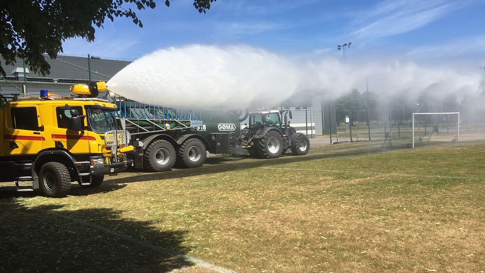 Tankbil sprutar vatten på planen vid Kombihallen på Halmstad Arena.