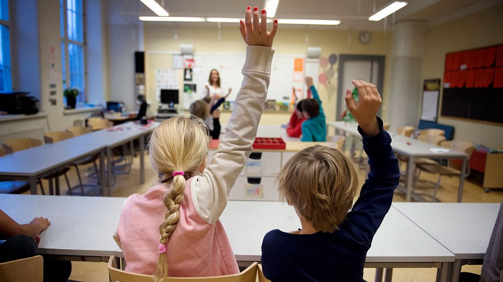 Elever räcker upp handen i klassrum