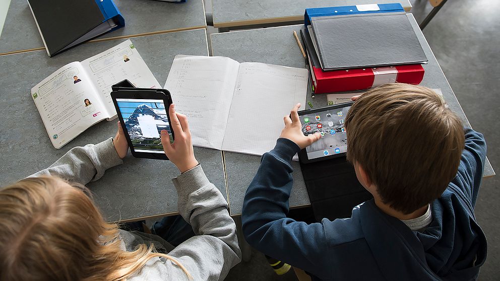 Skolelever med böcker och surfplattor