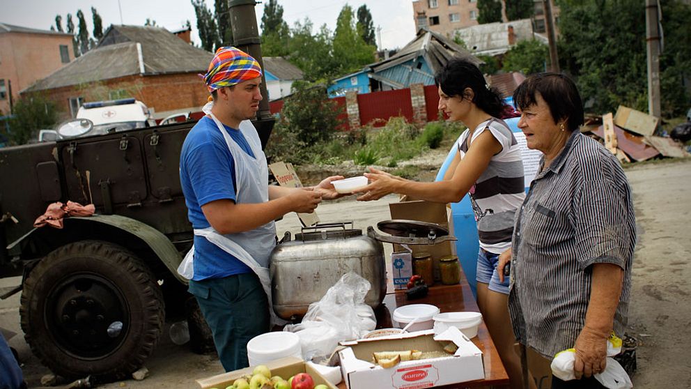 En hjälparbetare delar ut mat och vatten till invånare som drabbats av översvämningen i staden Krymsk.
