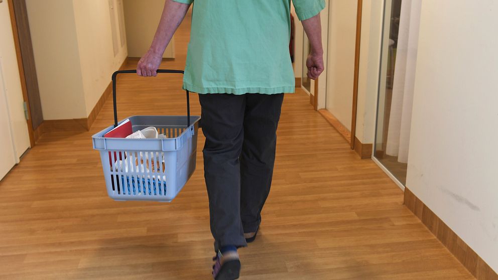 På bilden syns en anställd inom vård och omsorg gå med en shoppingkorg med mediciner i.