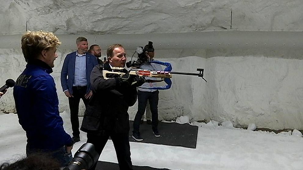 Stefan Löfven siktar med ett skidsskyttegevär.