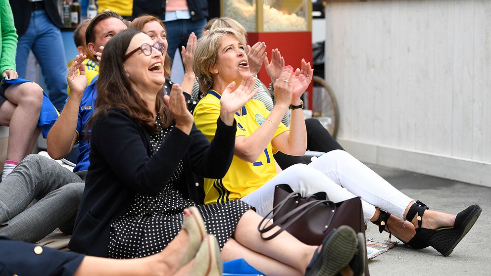 Skolminister Anna Ekström och socialminister Annika Strandhäll tittar på VM-matchen mellan Sverige och Schweiz i Almedalen.