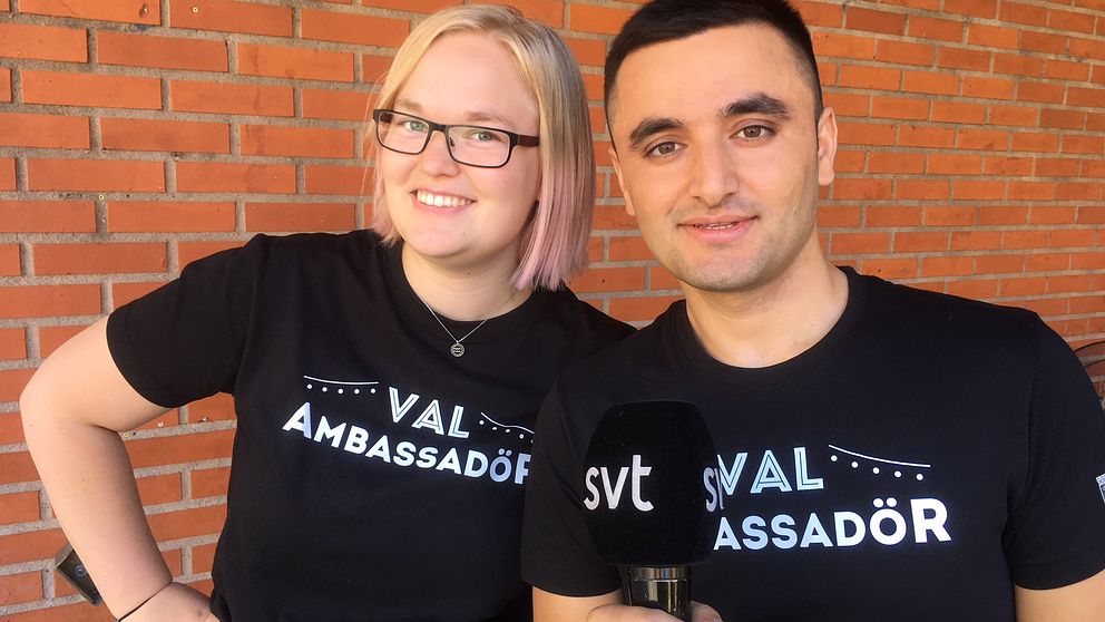 en tjej och en kille framför en tegelvägg, i t-shirtar med texten ”val-ambassadör”