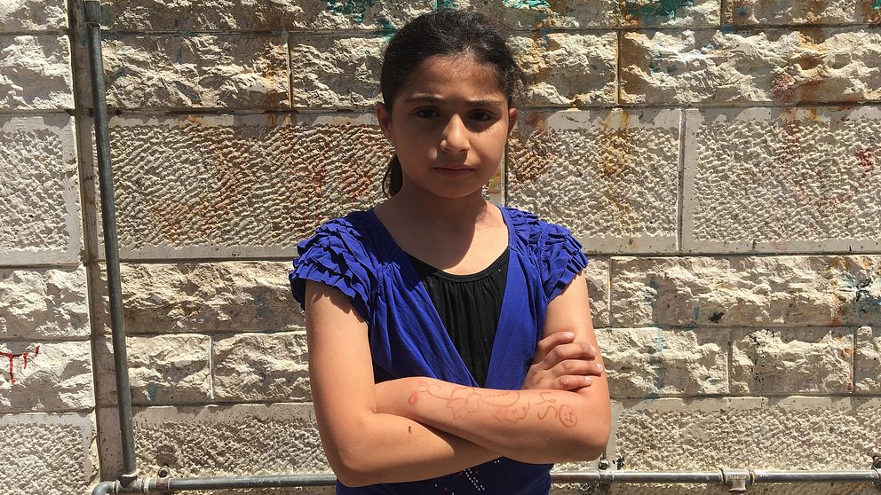 Bild på en flicka som heter Shaheed Sahafi som står med armarna i kors mot en tegelvägg.