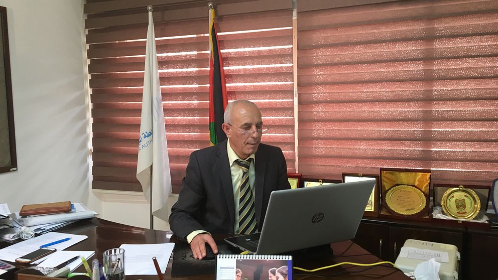 Bild på Rehby El Sheikh biträdande chef på Vattenverket i Gaza, som sitter på sitt kontor framför sin dator.