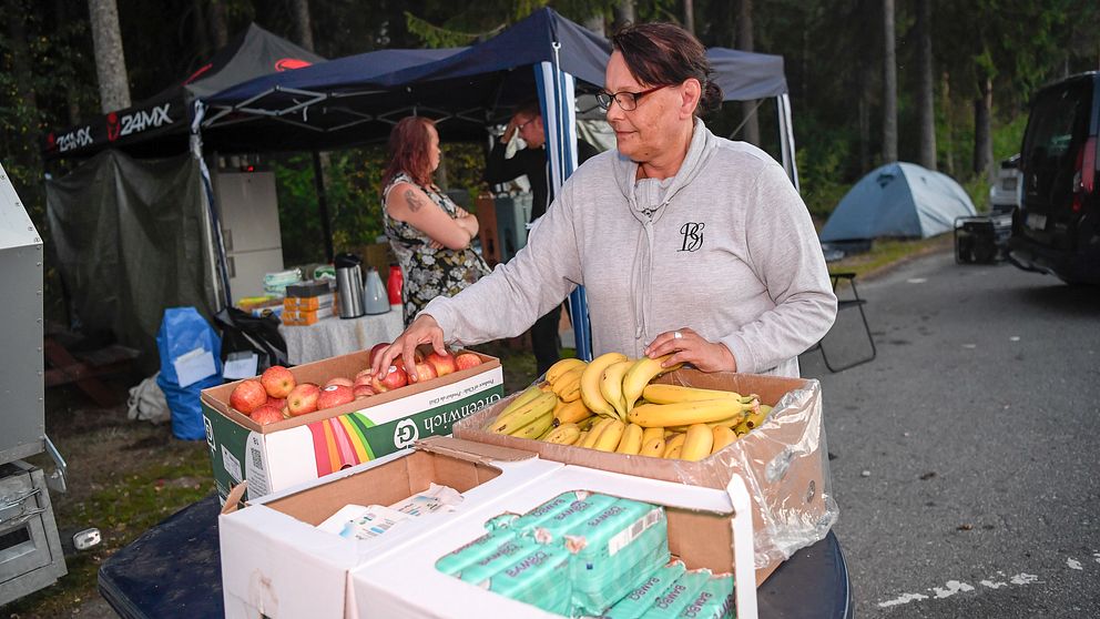 Kvinna står och gör i ordning lådor med frukt.