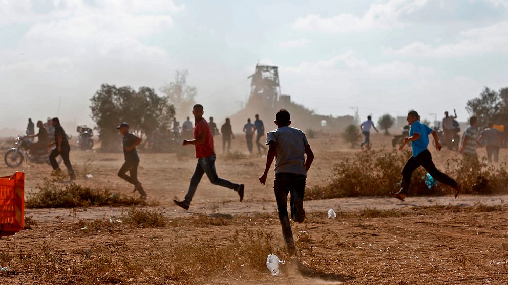Unga män som springer under protesterna längs Gazaremsan.