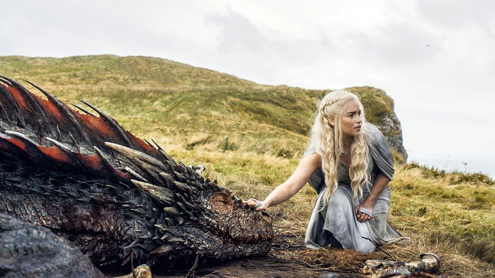 En bild från serien Game of Thrones där en av huvudpersonerna klappar en drake.