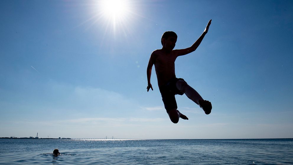 Barn hoppar ut i vatten under varmt väder.