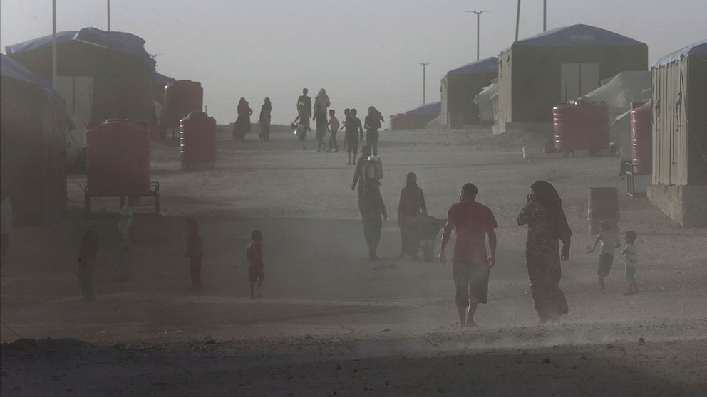 Människor går uppför en grusväg i ett flyktingläger i Syrien