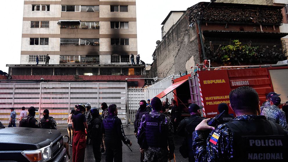 Militär och polis utanför en brandskadad byggnad i Venezuela.