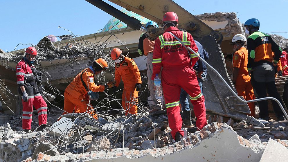 Räddningsarbetare söker efter offer i en kollapsad moské på Lombok.