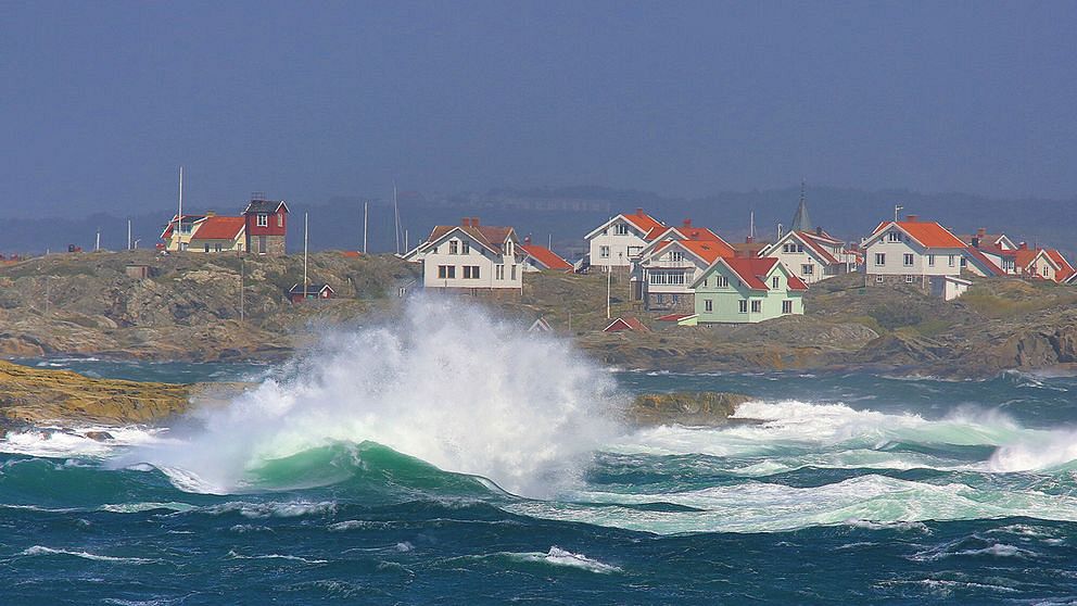 Hus vid vattnet och höga vågor.