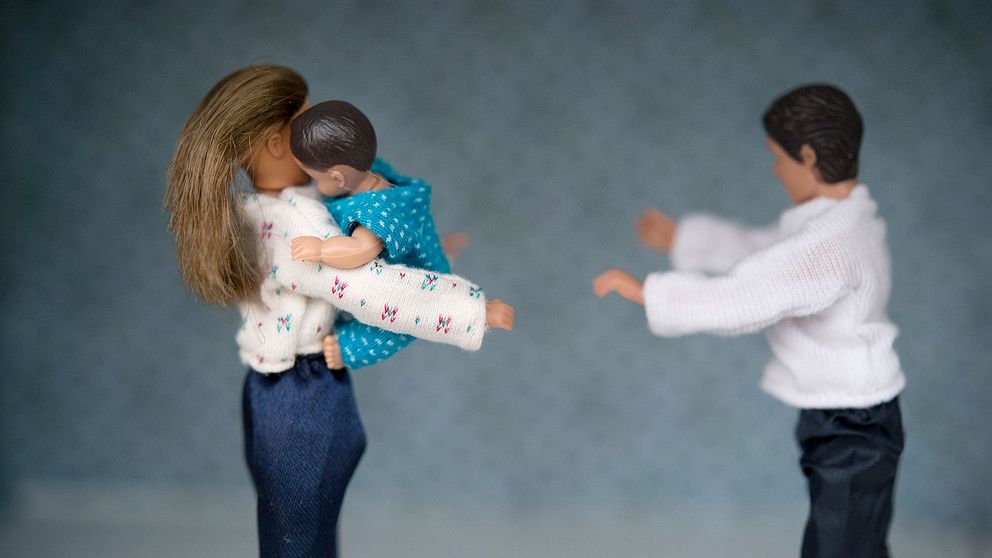 Dockor där en kvinnlig docka håller i ett barn och en manlig docka står mitt emot. Illustrerar vårdnadstvist.