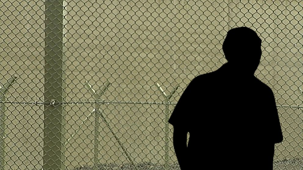 anonym silhuett av man syns mot fängelse-staket