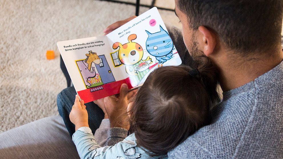 Pappa som läser i barnbok för sitt barn