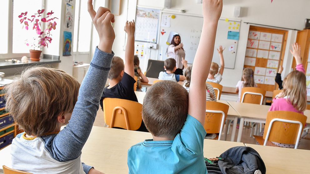 Skolklass med några elever som räcker upp händerna