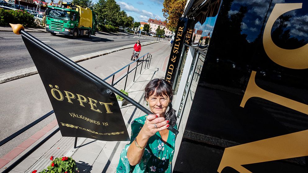 Ninni Nordeen Nyberg, butiksägare i Ljusdal, hänger öppet-flaggan utanför sin butik.