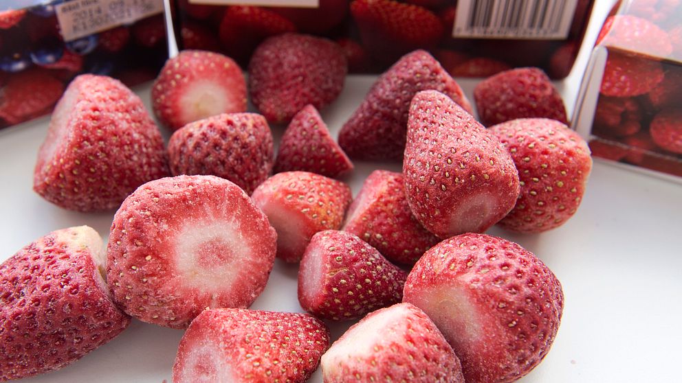 Röda frysta jordgubbar ligger på en skiva.