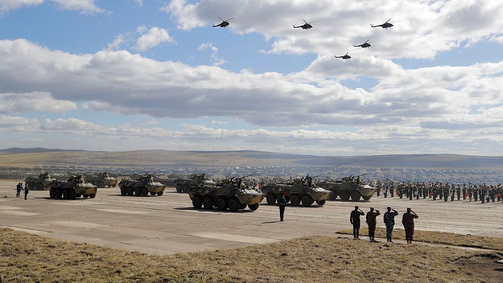 En stor militärövning med stridsvagnar, helikoptrar och infanterister på ett fält.