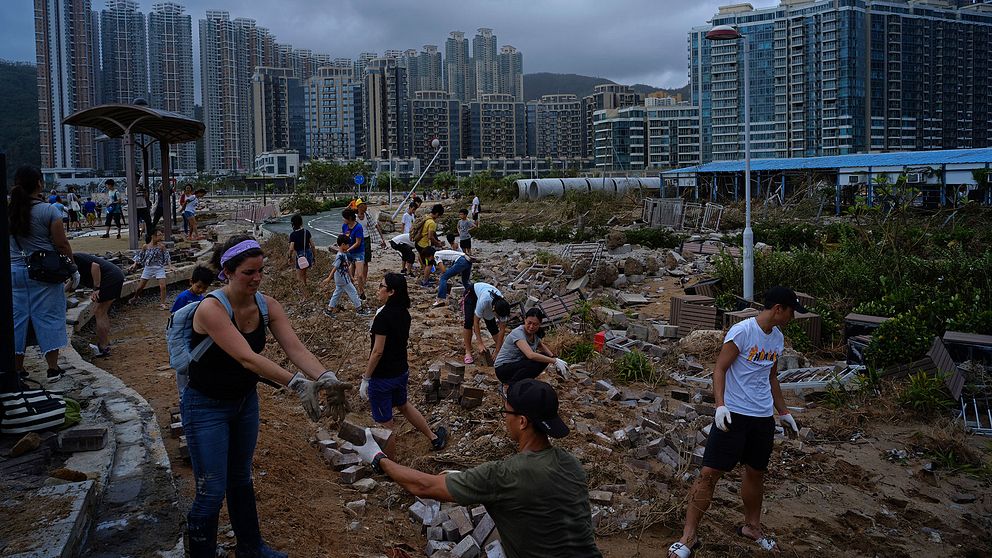 Människor i Hongkong hjälps åt för att städa undan bråte efter den tropiska orkanens framfart.