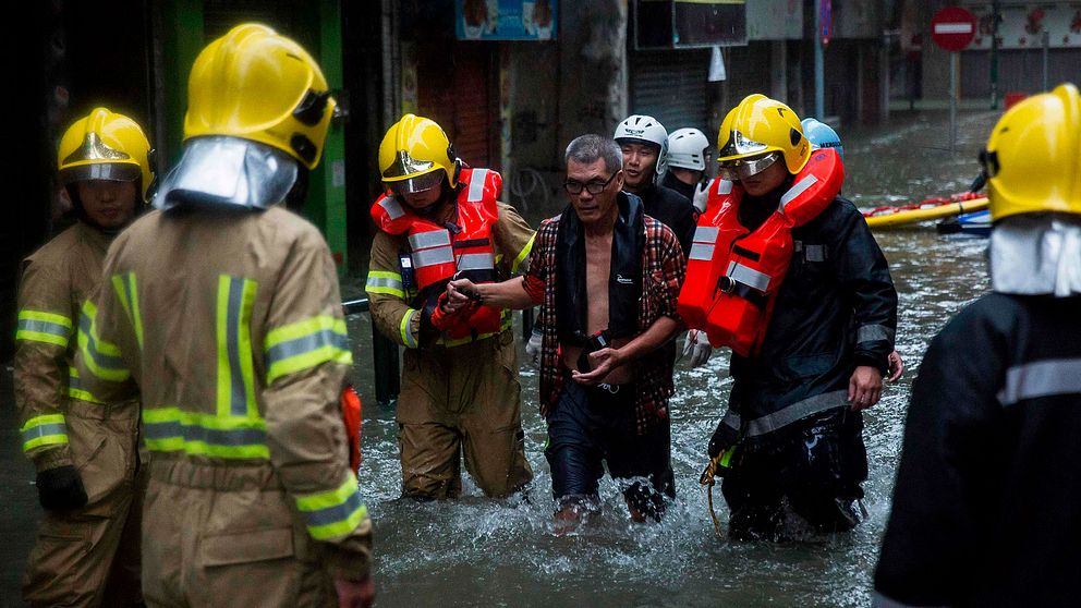 En butiksägare i Macau blir upphämtad från ett översvämmat område av räddningstjänten.