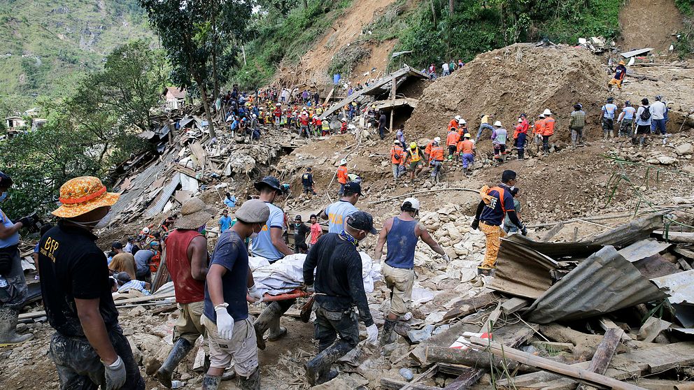Räddningsarbetare letar efter de försvunna människorna som begravdes i lermassor efter ett jordskred.