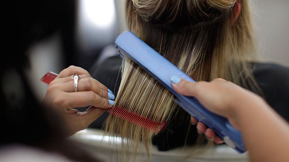 En frisör plattar håret på en kund.