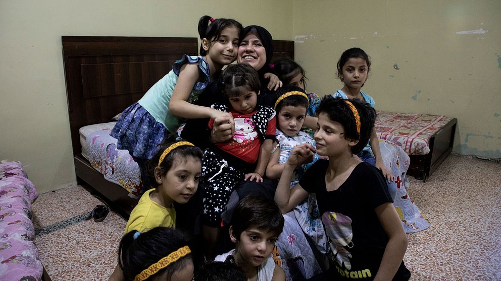 Joumana Makki, som driver ett barnhem för föräldralösa flickor i Aleppo, sitter omgiven av flera barn.