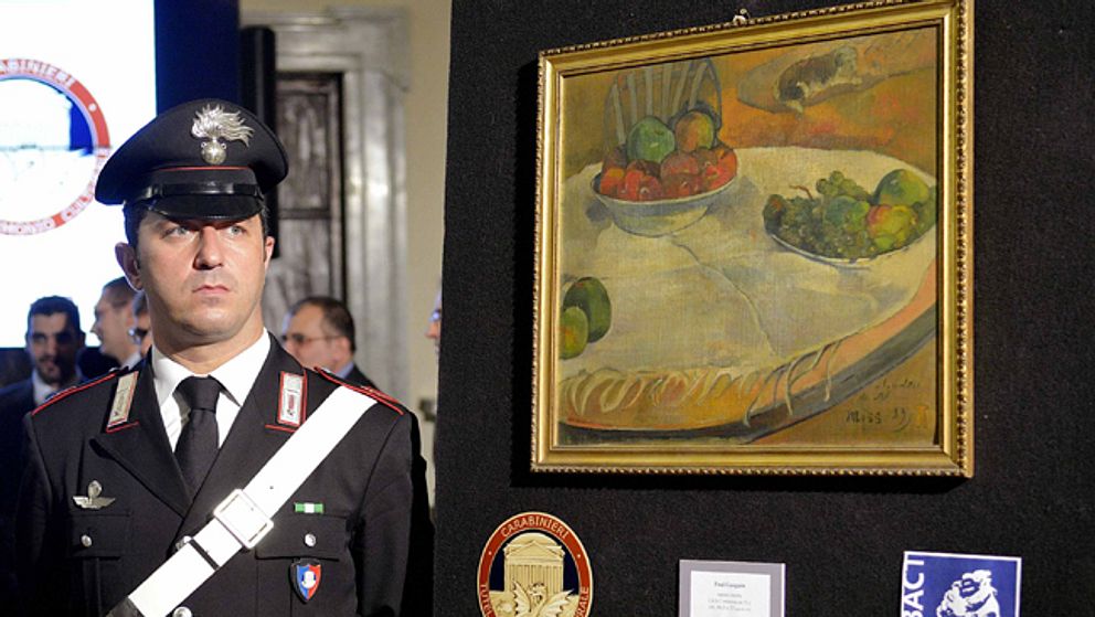 En italiensk carabinieri framför Paul Gaugains målning som hittades i fabriksarbetaren kök på Sicilien.