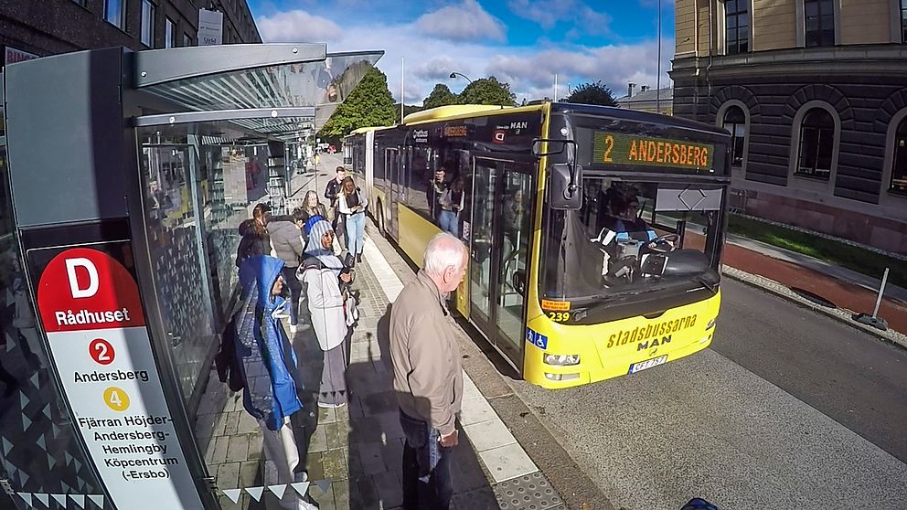 Stadsbuss i Gävle stannar vid hållplats i centrum där passagerare väntar på att stiga på.