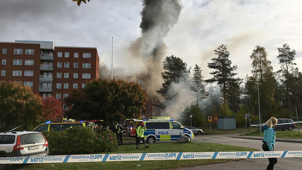 avspärrning, polisbilar och folk vid tegelhus, stor rökpelare