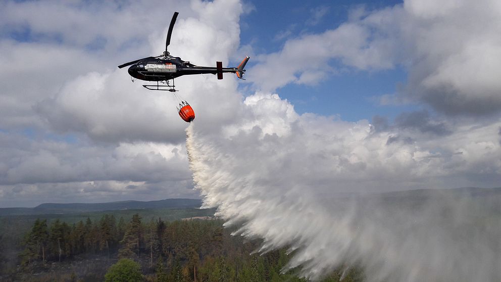 flygbild på helikopter som vattenbombar skogen