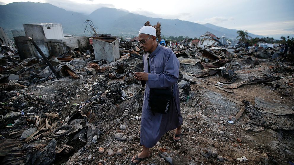 En man kliver över rasmassorna av ett hus i Palu, Indonesien.