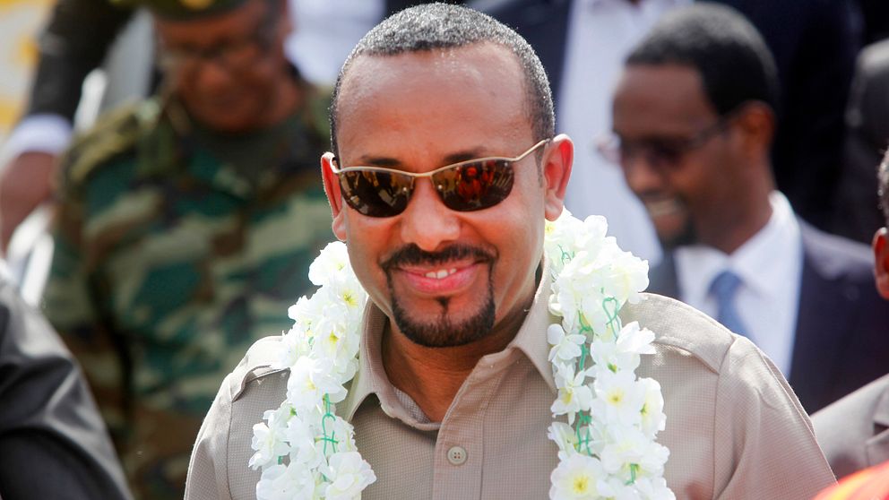 Abiy Ahmed med blommor runt halsen och solgalsögon.