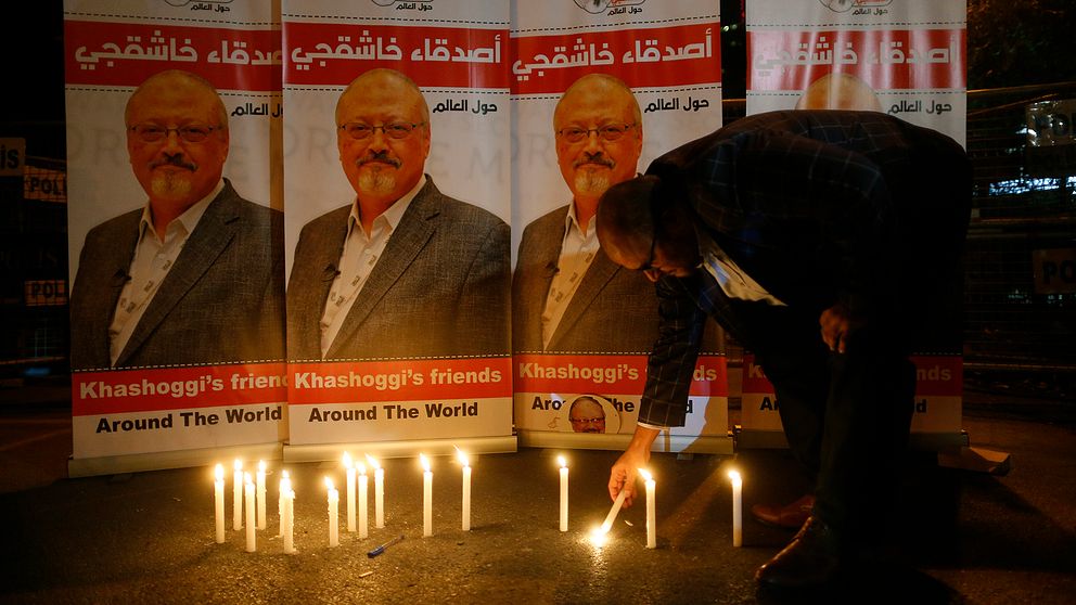En man tänder ljus framför porträtt av saudiske journalisten Jamal Khashoggi, som misstänks ha mördats.