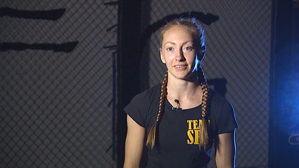ung kvinna sitter belyst för intervju i en nätad MMA-ring