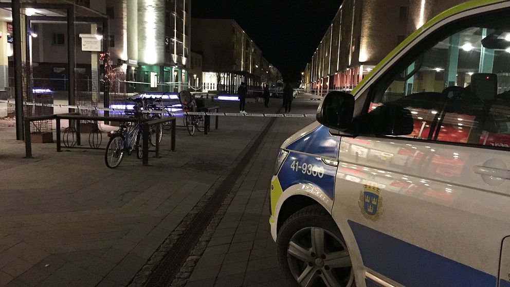 Polisbil och avspärrningsband på nattlig gata.