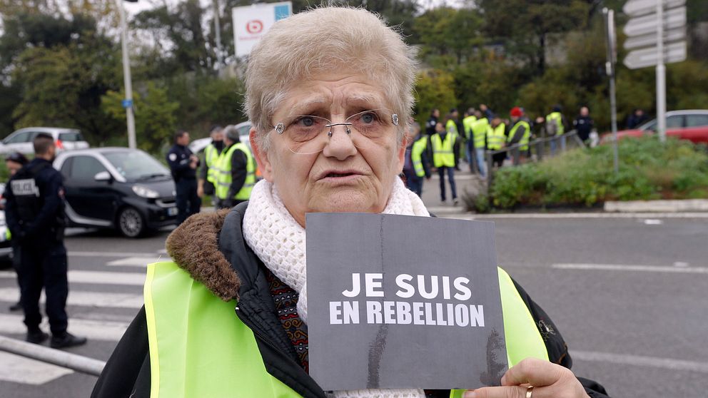 En kvinna som demonstrerar mot bensinpriserna håller upp en skylt med texten ”jag är med i upproret”.