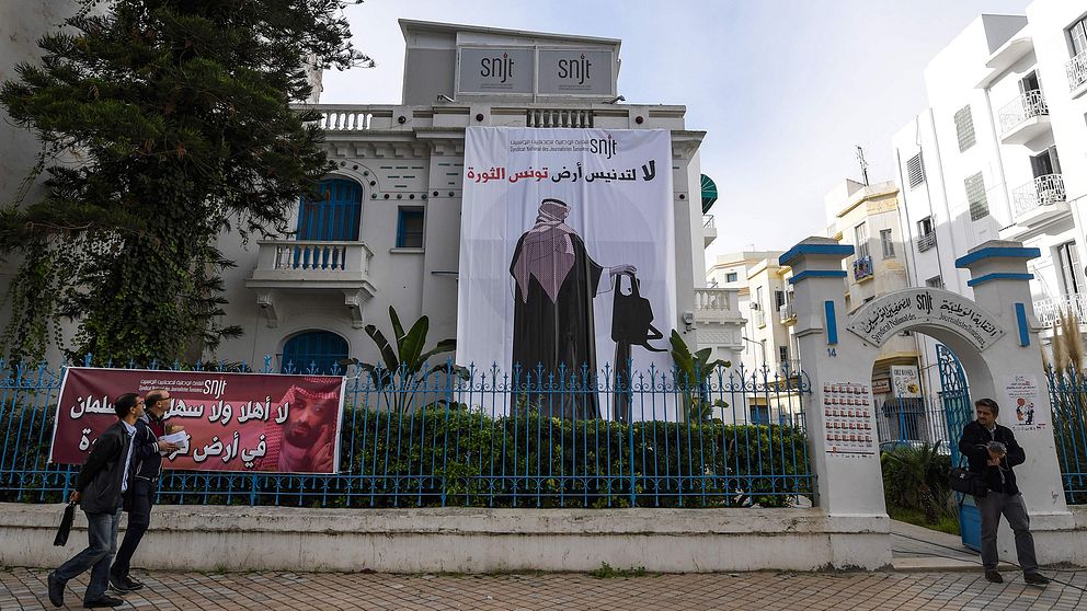 På tunisiska Journalistförbundets fasad hänger en banderoll föreställande Saudiarabiens kronprins, hållandes i en motorsåg.
