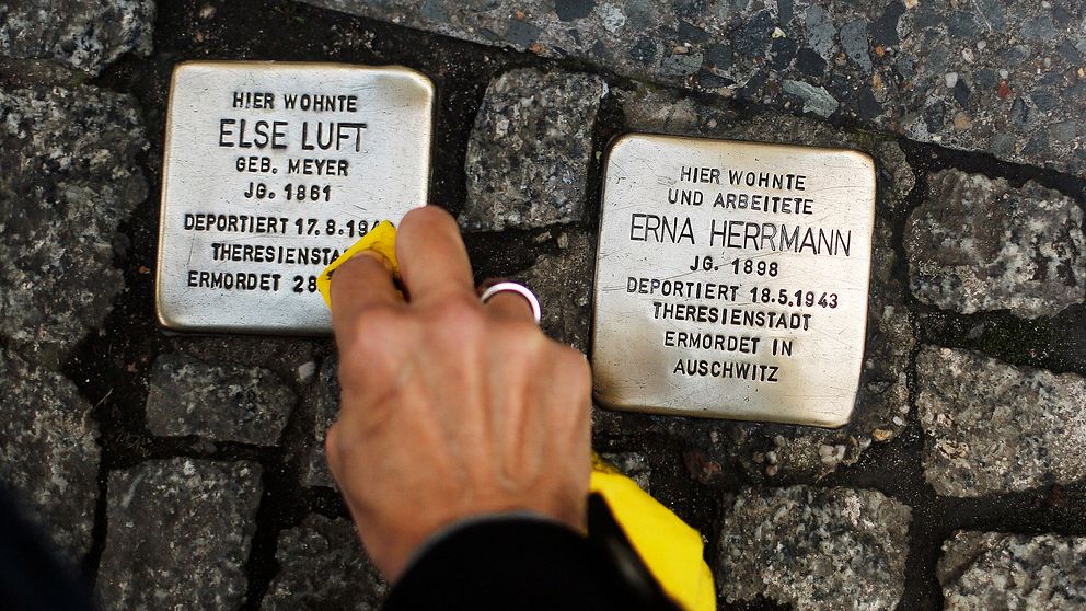 En hand putsar gatustenar till minne av de som dödades under Nazityskland.