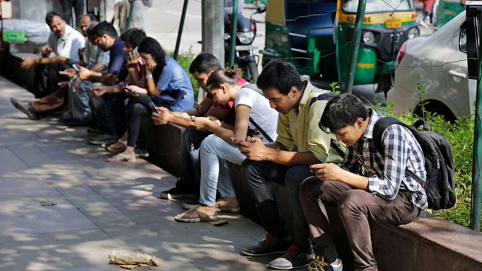 Personer använder sina telefoner i New Delhi