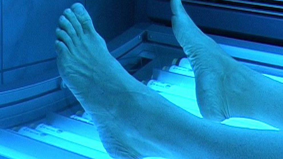 Fötterna på en person som solar solarium.