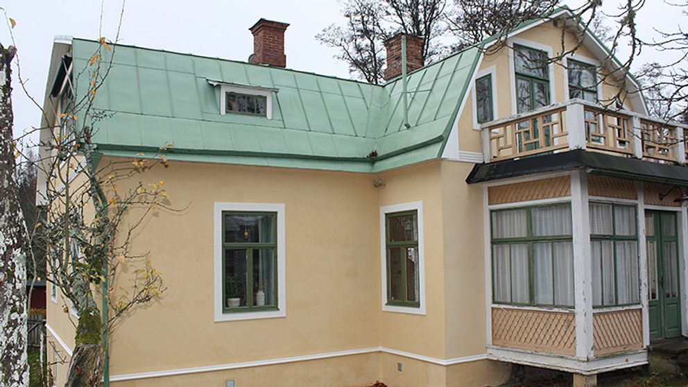villa med gul rappad fasad och grönt plåttak