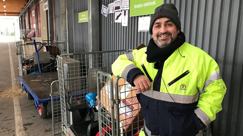Rickard Hagman i reflexjacka framför en bur med elektronikskräp.