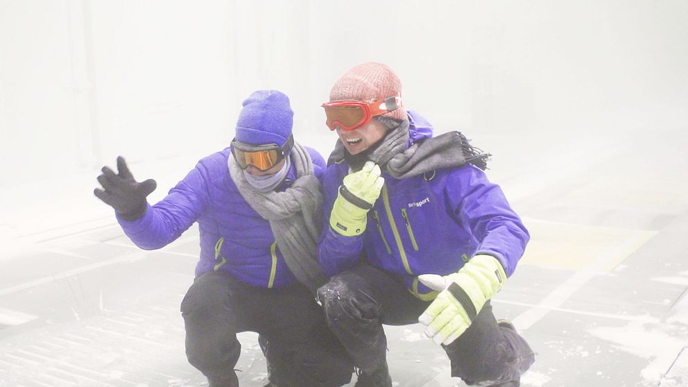 SVT:s meteorolog Nils Holmqvist och reporter Torbjörn Averås Skorup i klimattunneln där det blåser stark vind och snöar.