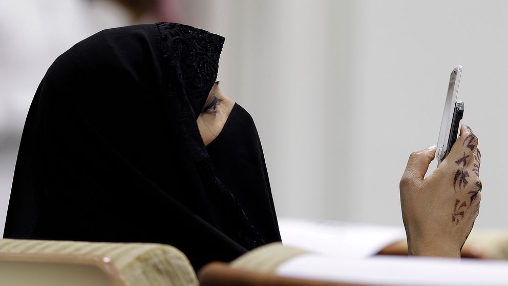 En kvinna i niqab tittar i sin mobil.