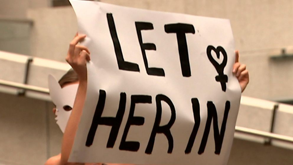 Demonstrant i Australien håller upp en skylt där det står ”släpp in henne” och refererar till saudiska Rahaf al-Qunun.