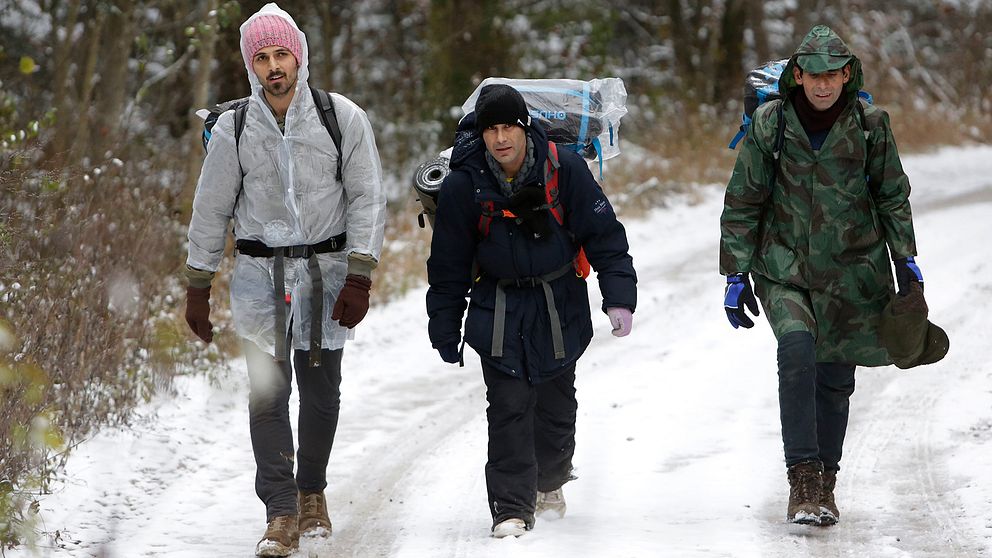Tre män bär på sin packning i snön på väg mot gränsen till Kroatien.